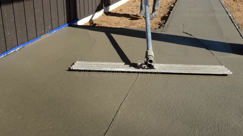 Concrete bull float used on new cement concrete by a construction worker. stock video footage