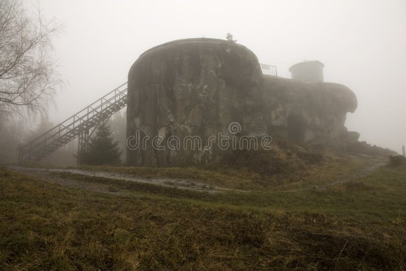 This atmospheric image captures the N-D-S 72 Mustek infantry bunker, part of the Dobrosov fortress, shrouded in dense fog. The imposing concrete structure and metal access stairs emerge mysteriously from the mist, conveying a sense of history and solitude. It is ideal for themes of military history, cold war, historical sites, or mysterious landscapes. Metal n stock images, royalty-free photos and pictures