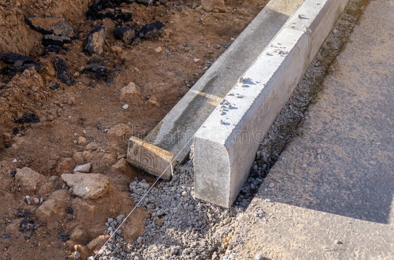 Concrete curb installation. String line level guide is stretched parallel  to the line of course Stock Photo