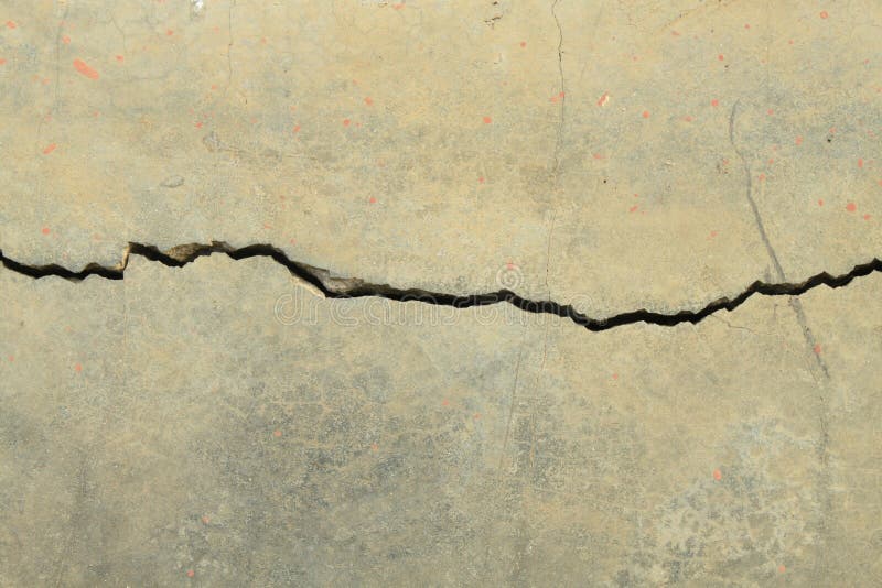 Vertical image of cracks in the concrete floor of a dilapidated building