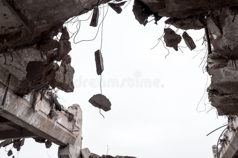 Concrete fragments on metal fittings with the remains of a building against a gray sky. Background