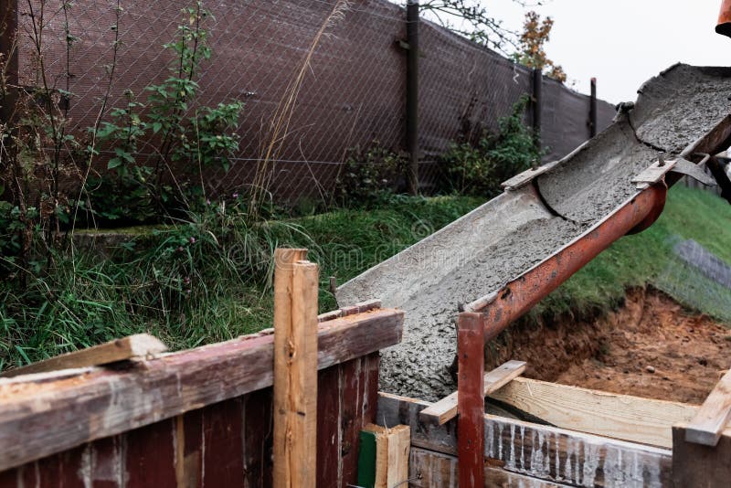 The concrete mixer unloads the concrete through a chute into a timber formwork with metal reinforcement to create a solid royalty free stock photos