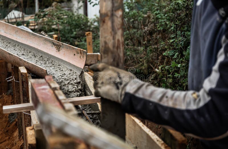 The concrete mixer unloads the concrete through a chute into a timber formwork with metal reinforcement to create a solid royalty free stock photo
