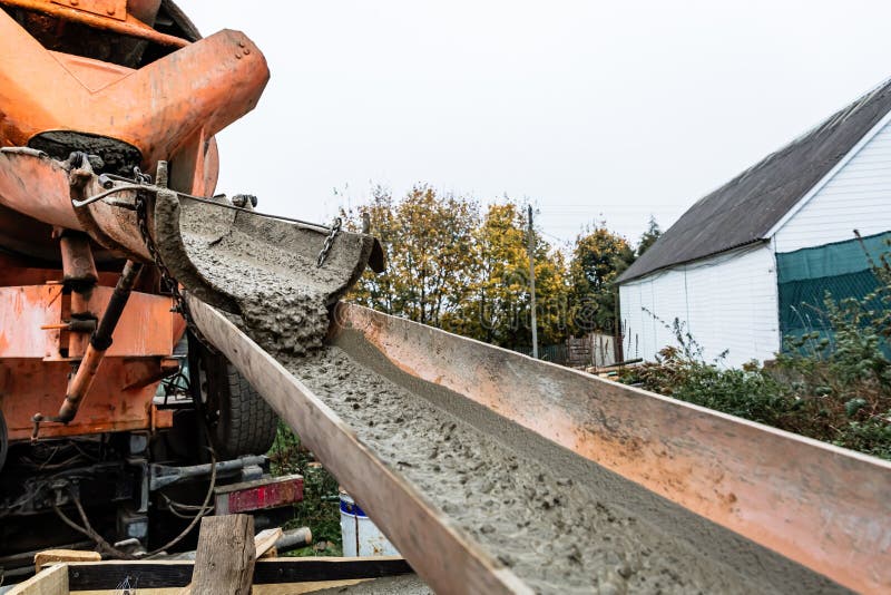 The concrete mixer unloads the concrete through a chute into a prepared container at the construction site. Building process using stock photo