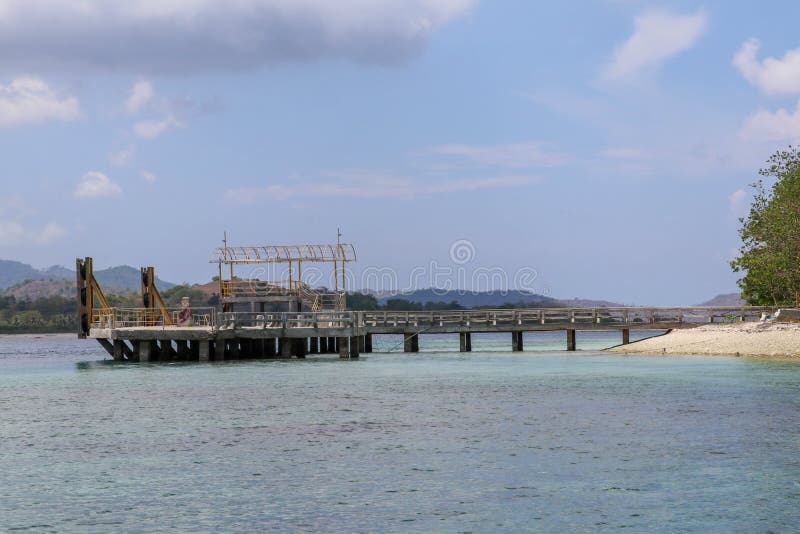Concrete pier on the beach with an access bridge in shallow water. Old concrete pier on the sea. Gili Layar island near Lombok.