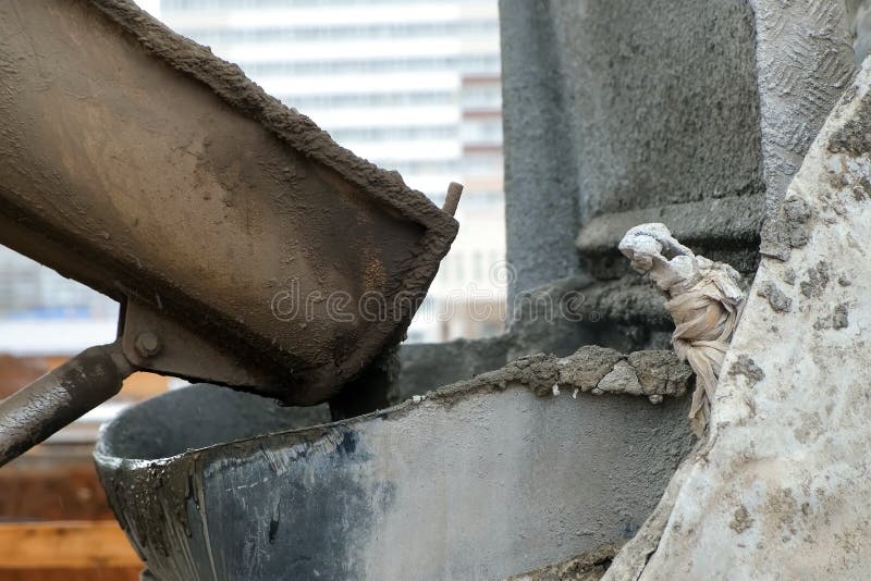 Concrete truck chute pouring wet cement Mix into metal bucket