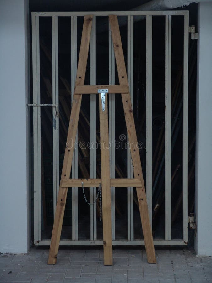 Condizione alta di legno del cavalletto contro una porta del garage del metallo nel bianco immagine stock Condizione alta di legno del cavalletto contro una porta del garage del metallo nel bianco immagine stock