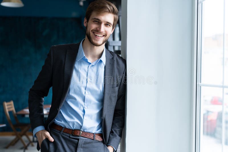 Condizione bella professionale sicura dell'uomo d'affari vicino alla finestra nel suo ufficio fotografie stock libere da diritti Condizione bella professionale sicura dell'uomo d'affari vicino alla finestra nel suo ufficio fotografie stock libere da diritti