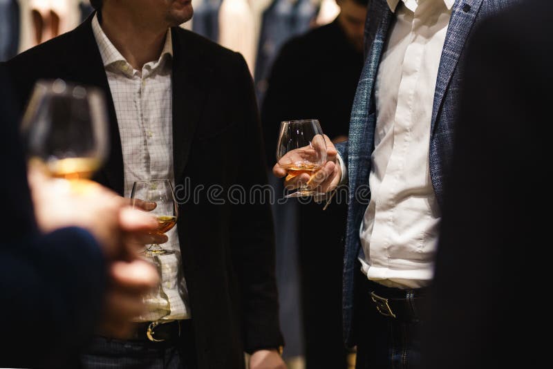Condizione della gente che chiacchiera ad una cena di affari che tiene l'assaggio di vetro di vino e del whiskey e che degustatin immagine stock Condizione della gente che chiacchiera ad una cena di affari che tiene l'assaggio di vetro di vino e del whiskey e che degustatin immagine stock