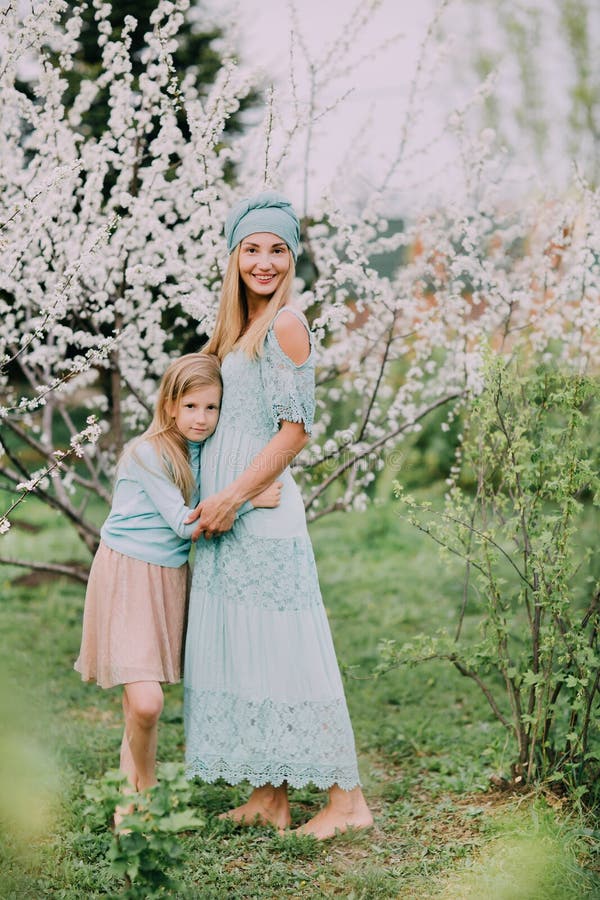 Condizione felice della mamma con la figlia su un parco della ciliegia della molla fotografia stock Condizione felice della mamma con la figlia su un parco della ciliegia della molla fotografia stock