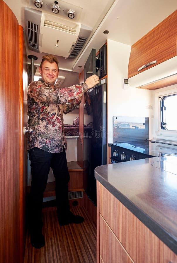 Middle aged male standing in the kitchen corner inside of recreational vehicle motor home. Travelers journey and adventure, spending time, living and traveling in camper van concept. Middle aged male standing in the kitchen corner inside of recreational vehicle motor home. Travelers journey and adventure, spending time, living and traveling in camper van concept