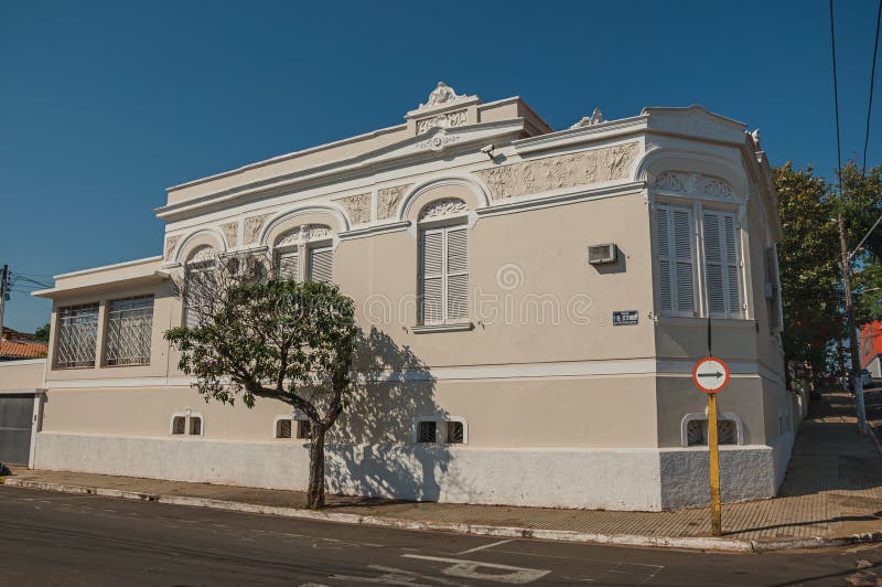 Condomínio de canto ornamentado velho em uma rua vazia com as árvores no passeio em São Manuel fotografia de stock Condomínio de canto ornamentado velho em uma rua vazia com as árvores no passeio em São Manuel fotografia de stock