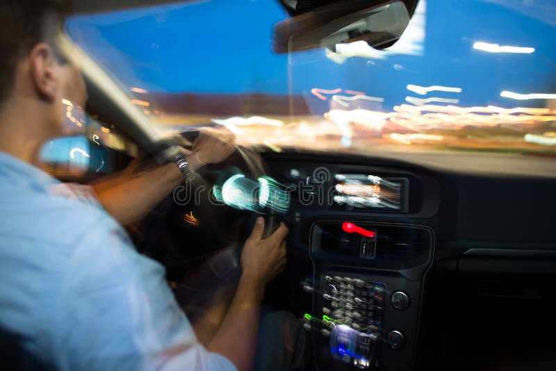 Conducendo un'automobile alla notte - giovane che conduce la sua automobile moderna fotografie stock Conducendo un'automobile alla notte - giovane che conduce la sua automobile moderna fotografie stock