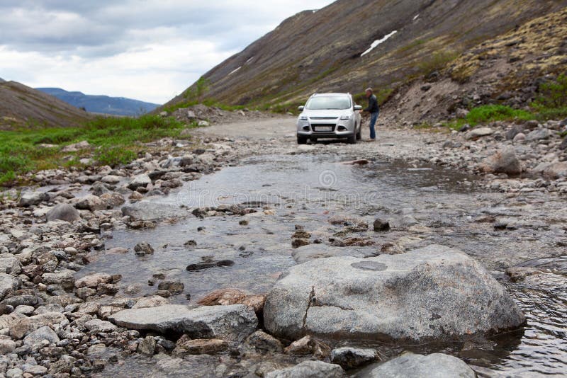 Conducteur se reposant dans la voiture pour conduire sur la rivière de montagnes image stock Conducteur se reposant dans la voiture pour conduire sur la rivière de montagnes image stock