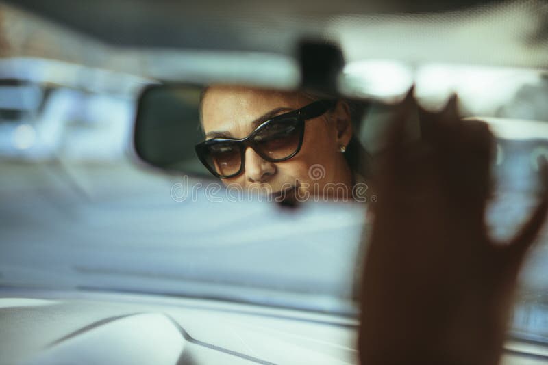 Conducteur supérieur de femme ajustant le miroir de voiture de vue arrière photo libre de droits Conducteur supérieur de femme ajustant le miroir de voiture de vue arrière photo libre de droits