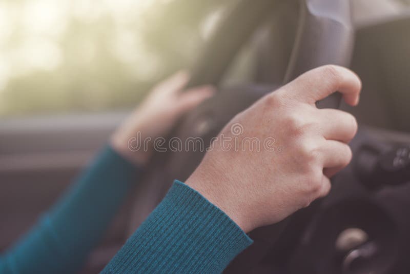 A condução segura, mulher prende o volante do carro