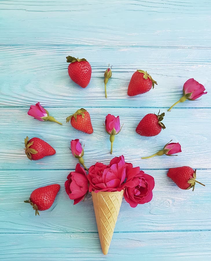 Cone for ice cream, strawberry, fresh rose flower pattern on a blue wooden