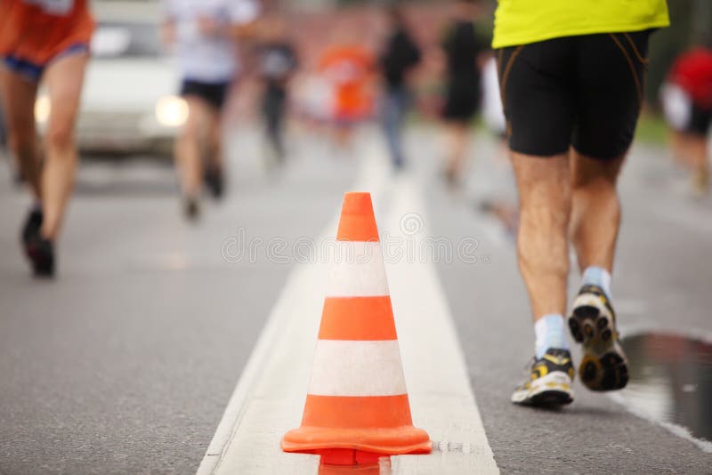 Cone on road between running people