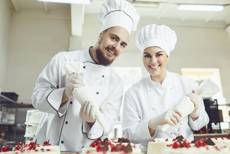 Confectioners with a bag for the cream will decorate the cake.