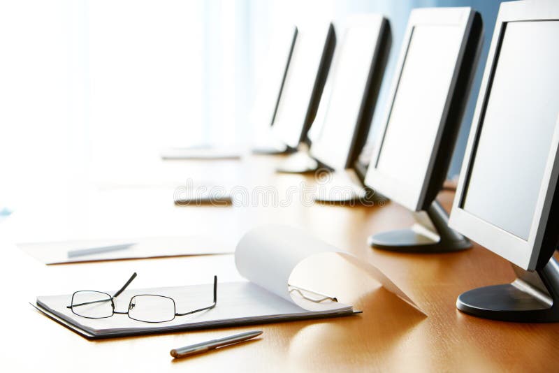 Close-up of workplace with notepad, pen, eyeglasses and monitors on it. Close-up of workplace with notepad, pen, eyeglasses and monitors on it