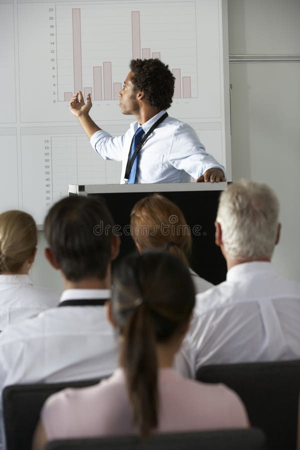 Conferência nova de Delivering Presentation At do homem de negócios imagem de stock royalty free Conferência nova de Delivering Presentation At do homem de negócios imagem de stock royalty free