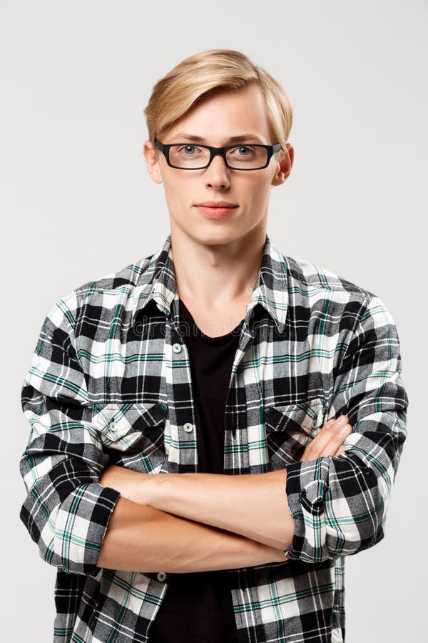 Confident blond handsome young man in glasses wearing casual plaid shirt with hands crossed on chest looking at camera