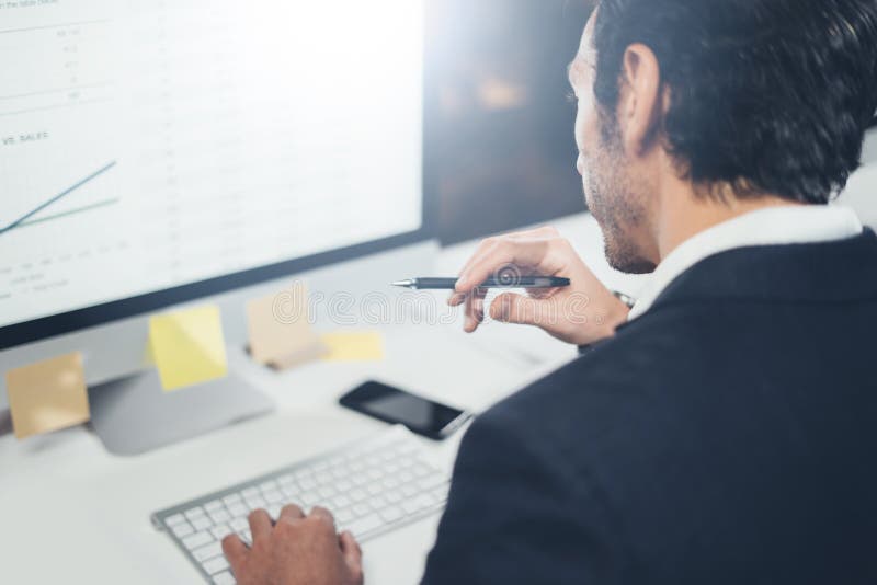 Confident businessman in formal wear thinking and working with desktop computer at modern lightful office.Horizontal royalty free stock photography Confident businessman in formal wear thinking and working with desktop computer at modern lightful office.Horizontal royalty free stock photography