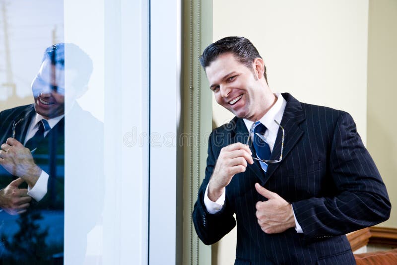 Confident businessman standing in office by window
