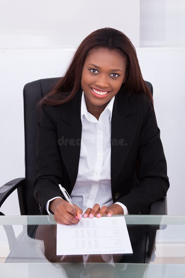 Confident businesswoman filling form at desk in office stock images Confident businesswoman filling form at desk in office stock images