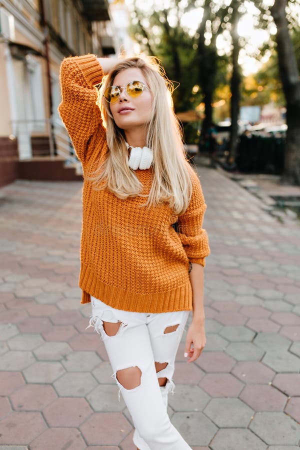 Confident cute lady in ripped white pants posing with pleasure before walk in park. Outdoor portrait of glamorous blonde stock images Confident cute lady in ripped white pants posing with pleasure before walk in park. Outdoor portrait of glamorous blonde stock images