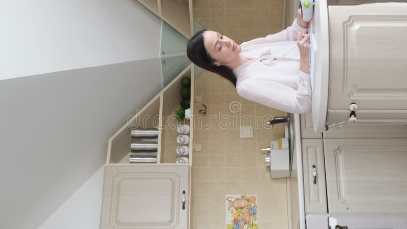 Successful lady freelancer sitting at the desk in her kitchen. Vertical video stock footage