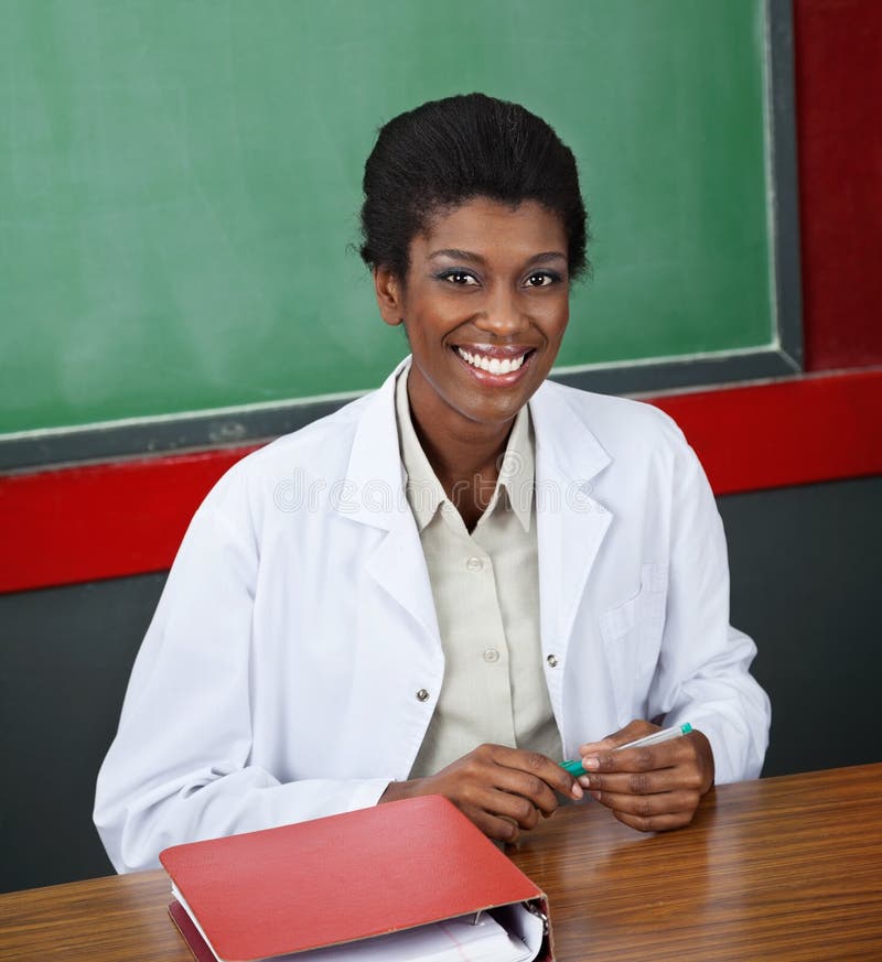 Confident Female Professor Sitting At Desk stock photos Confident Female Professor Sitting At Desk stock photos