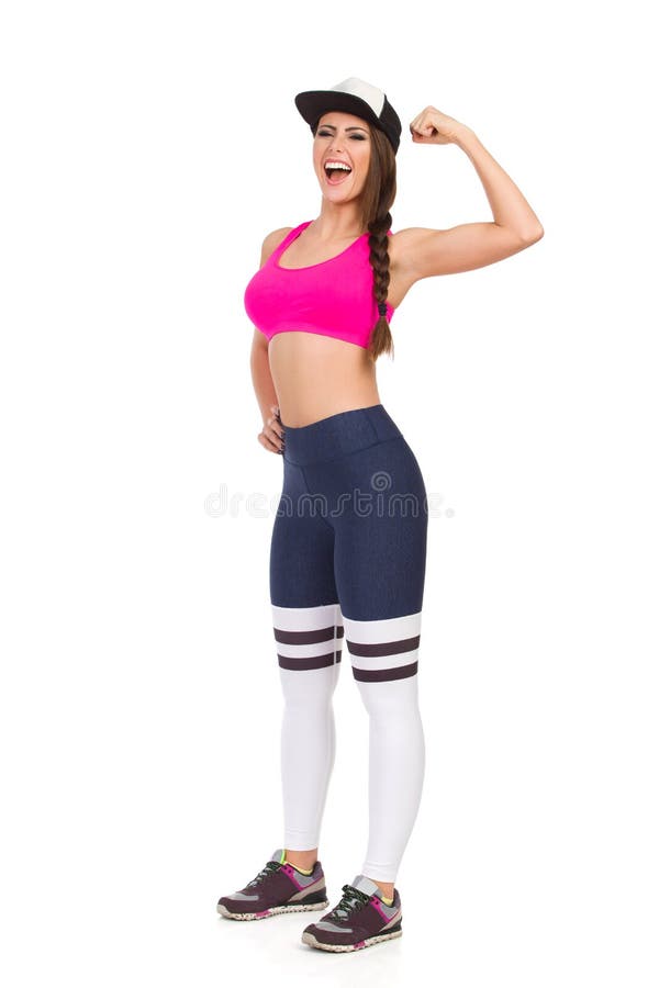 Confident fitness woman in sports clothes and baseball cap is flexing muscle and shouting. Full length studio shot isolated on white, strong, looking, camera, laughing, mouth, open, clothing, beautiful, gym, success, winning, sportswear, leggings, striped, healthy, pink, bra, tank, top, blue, happy, smiling, gesture, sneakers, standing, attractive, young, adult, person, cut, caucasian. Confident fitness woman in sports clothes and baseball cap is flexing muscle and shouting. Full length studio shot isolated on white, strong, looking, camera, laughing, mouth, open, clothing, beautiful, gym, success, winning, sportswear, leggings, striped, healthy, pink, bra, tank, top, blue, happy, smiling, gesture, sneakers, standing, attractive, young, adult, person, cut, caucasian