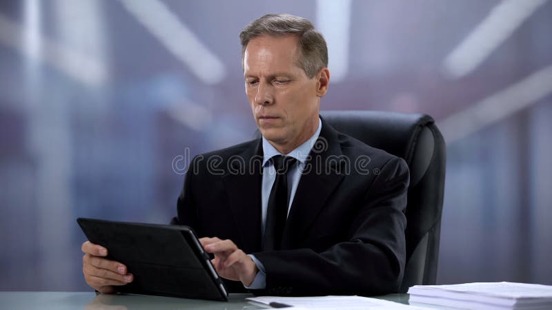 Confident male boss working on tablet pc at office desk, online documentation stock images