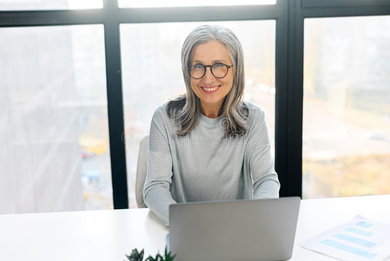 Confident mature female manager ceo sitting at desk indoor royalty free stock image