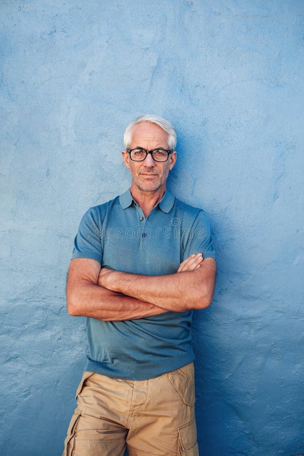 Confident mature man standing against a blue background