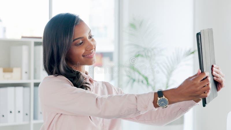 Confident woman taking selfies on digital tablet in modern office. Young woman using app to take a new profile picture stock video