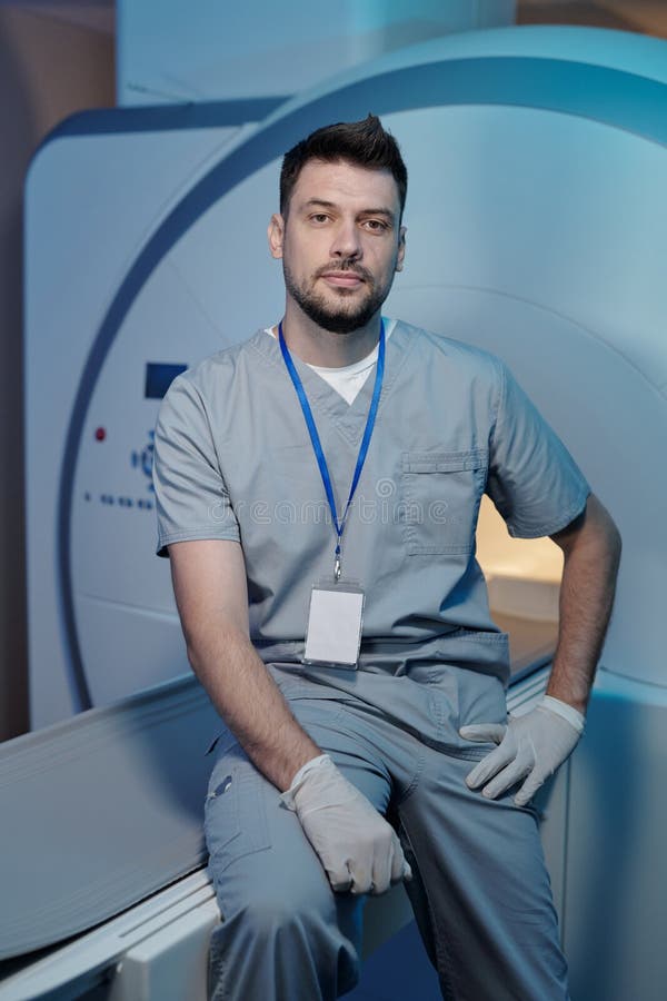 Confident Worker of Medical Laboratory Sitting on Table of Ct Equipment