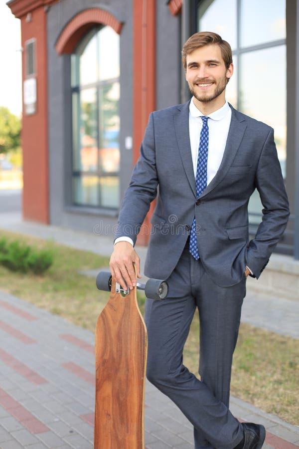 Confident young businessman walking on the street, using longboard. stock image Confident young businessman walking on the street, using longboard. stock image