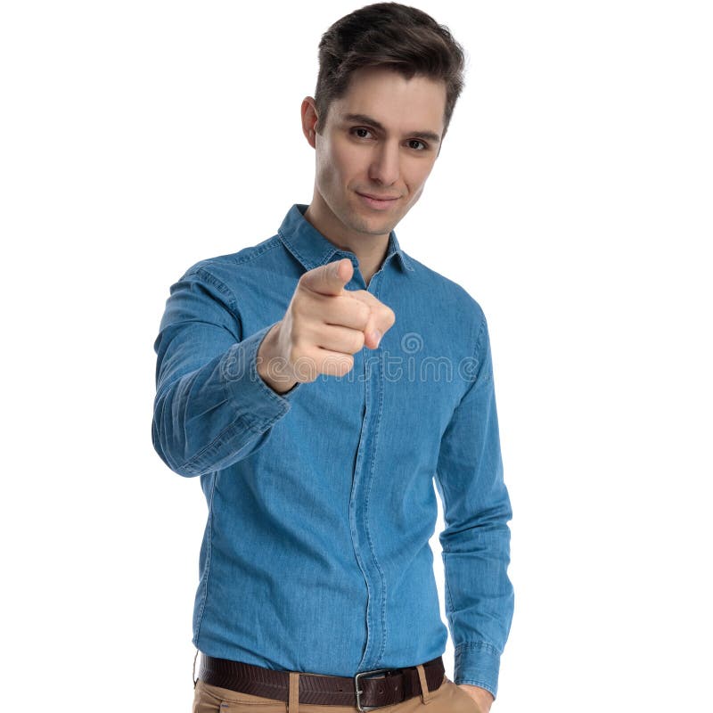 Confident young man in blue shirt smiling and pointing finger royalty free stock image Confident young man in blue shirt smiling and pointing finger royalty free stock image