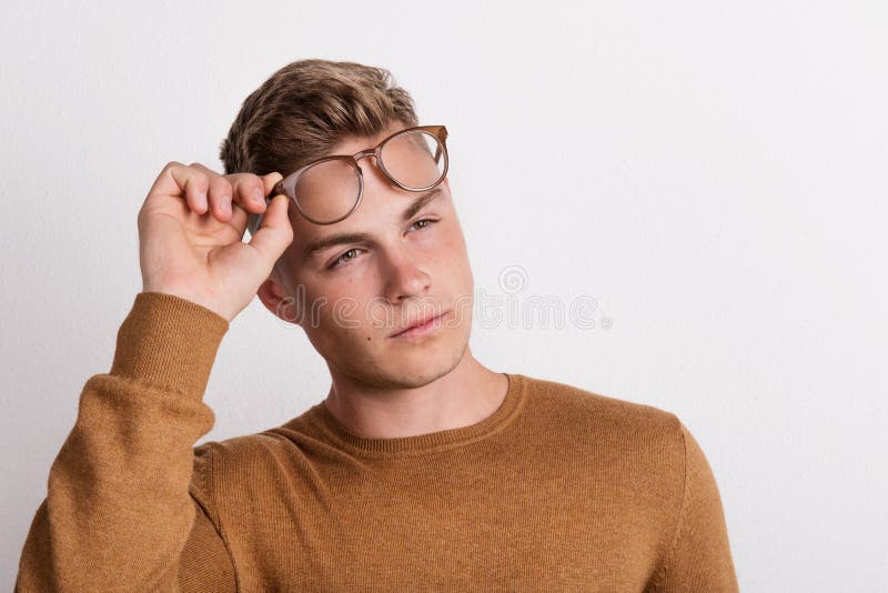 A Confident Young Man in a Studio, Holding Glasses on His Forehead