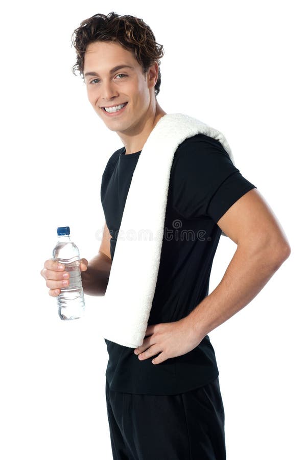 Confident young sporty guy looking at you as he poses with water bottle