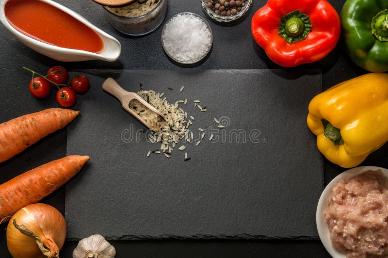 Configuração lisa, vista superior Fim acima Ingredientes para cozer as pimentas de sino enchidas alinhadas em torno de uma placa imagem de stock royalty free Configuração lisa, vista superior Fim acima Ingredientes para cozer as pimentas de sino enchidas alinhadas em torno de uma placa imagem de stock royalty free