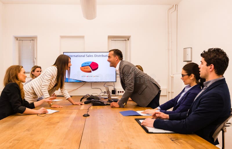 Conflict in the office : Business women arguing with her boss at meeting over latest sales figures with others watching embarassed