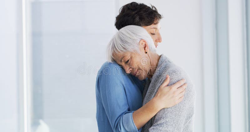 Conforto emotivo e donna che abbraccia la madre anziana in casa di riposo per dolore o perdita. Amore triste e donne immagini stock