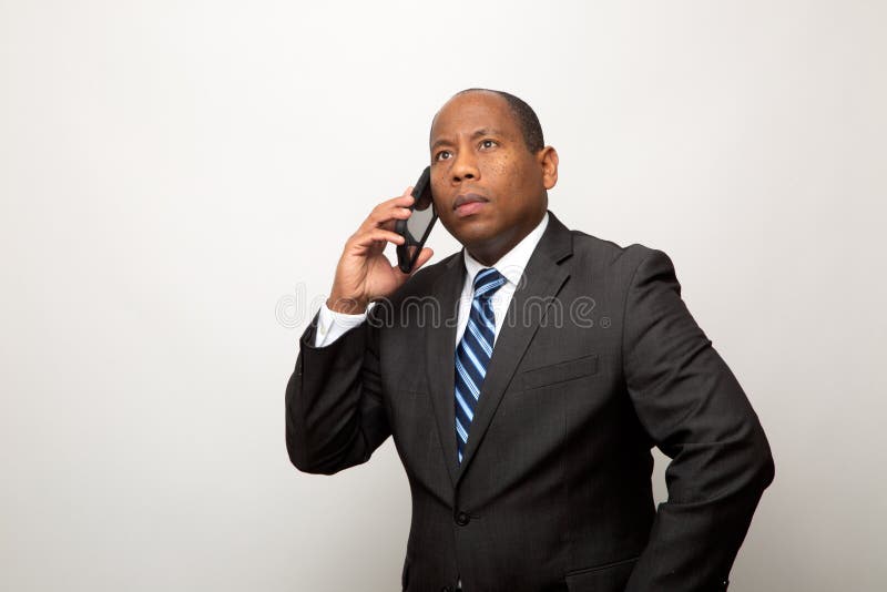 Confused African Business Man America Uses Smart Phone on Light Gray Background