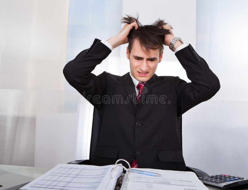 Confused Businessman Pulling Hair While Calculating Finances stock photography