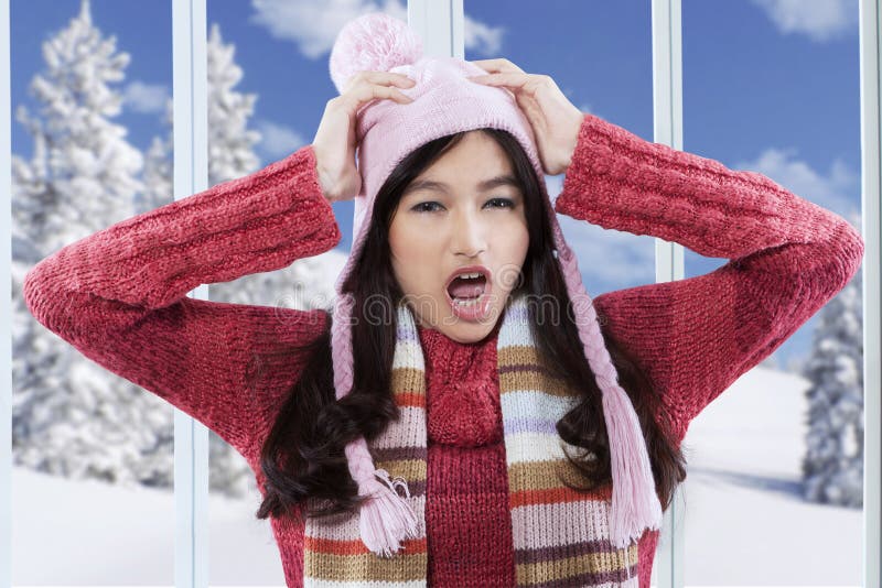 Portrait of confused girl wearing sweater and screaming at home while holding her head. Portrait of confused girl wearing sweater and screaming at home while holding her head