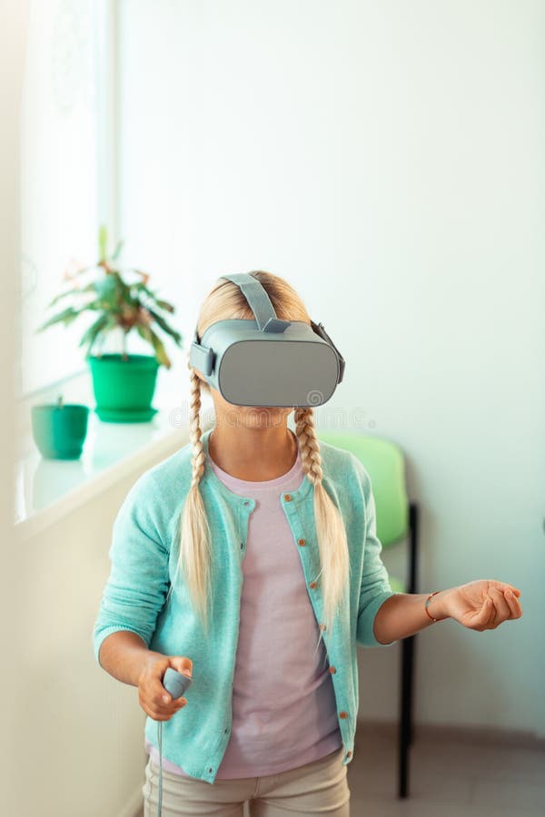 Confused schoolgirl trying to move in virtual reality. stock photos