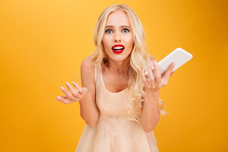 Confused shocked young blonde woman using mobile phone.